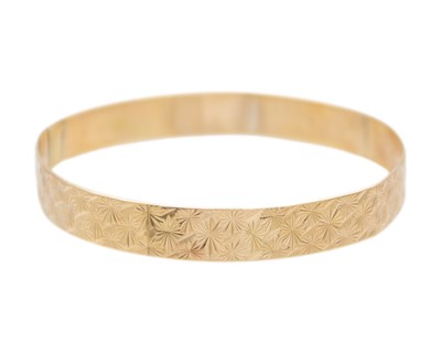 Lot 225 - A 9k gold engraved design bangle.