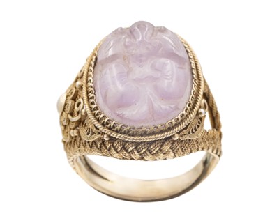 Lot 38 - A Chinese carved amethyst in a silver gilt adjustable ring.