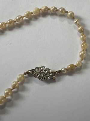 Lot 192 - A natural saltwater and cultured graduated pearl necklace, strung to a diamond clasp.