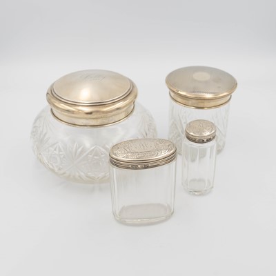 Lot 238 - A selection of four silver-lidded glass dressing table jars.