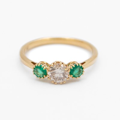 Lot 119 - An 18k three-stone diamond and emerald set ring.