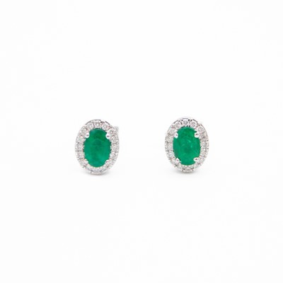Lot 122 - A pair of 18k white gold oval emerald and diamond cluster stud earrings.