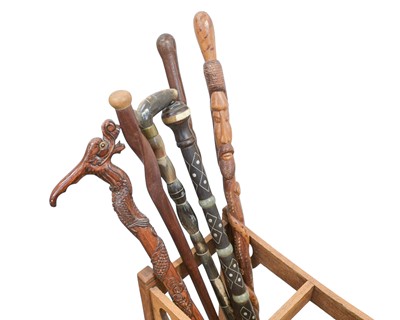 Lot 23 - A collection of walking sticks and canes in an Art Nouveau oak stand.