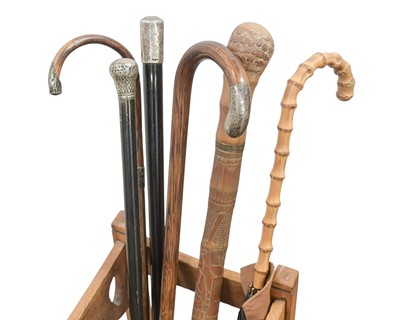 Lot 23 - A collection of walking sticks and canes in an Art Nouveau oak stand.