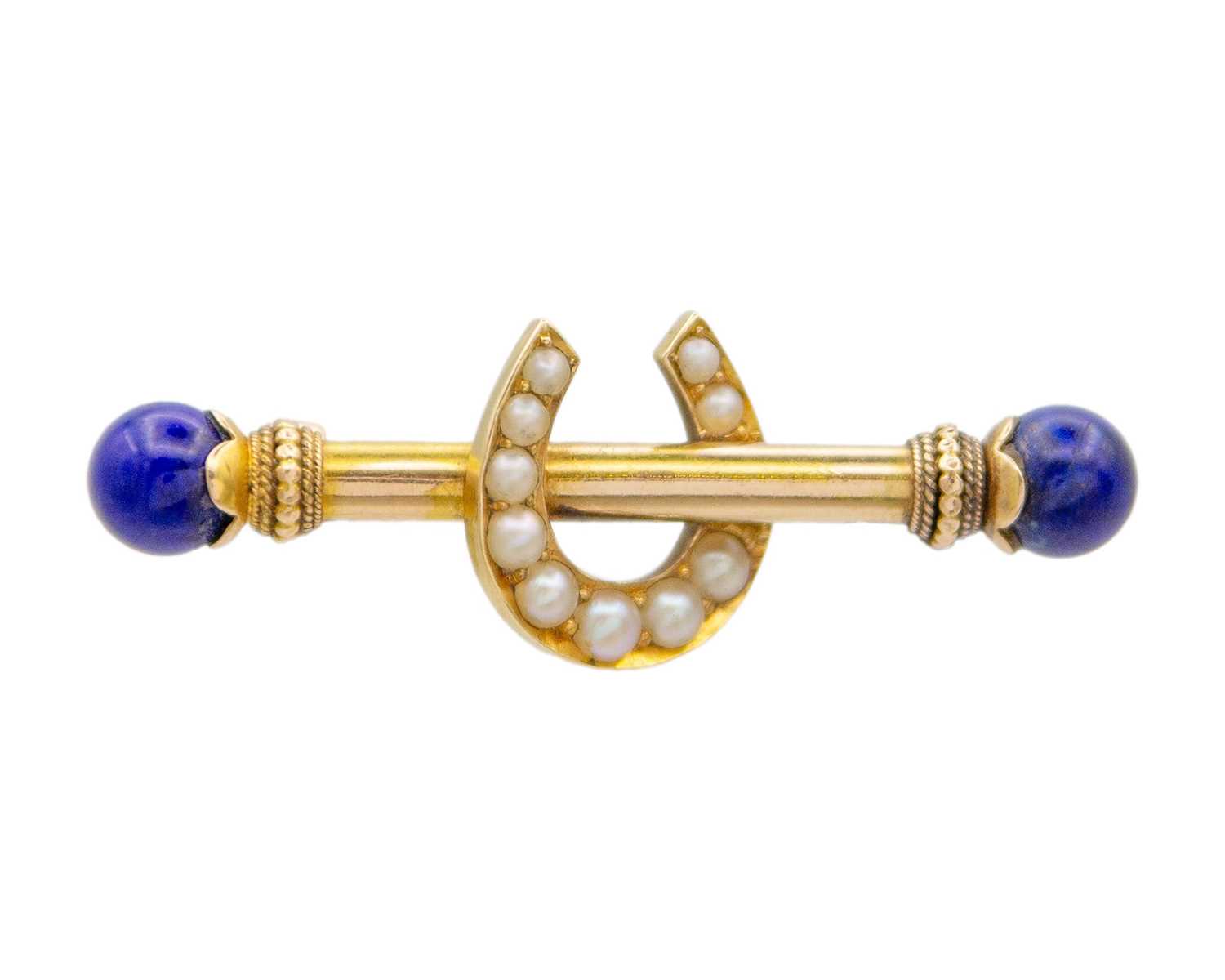 Lot 44 - A Victorian 15k gold horseshoe bar brooch set with lapis lazuli and seed pearls.