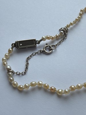 Lot 115 - A graduated pearl necklace strung to a white gold clasp set with two old mine-cut diamonds.