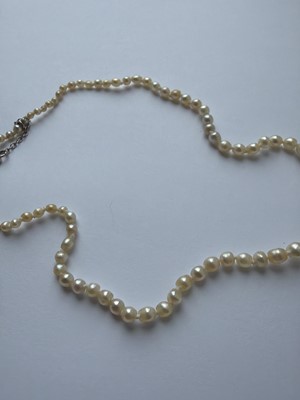 Lot 115 - A graduated pearl necklace strung to a white gold clasp set with two old mine-cut diamonds.