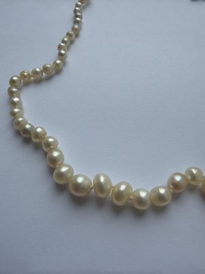 Lot 115 - A graduated pearl necklace strung to a white gold clasp set with two old mine-cut diamonds.