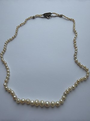 Lot 115 - A graduated pearl necklace strung to a white gold clasp set with two old mine-cut diamonds.