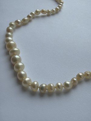 Lot 115 - A graduated pearl necklace strung to a white gold clasp set with two old mine-cut diamonds.