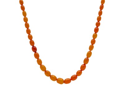 Lot 148 - A long egg yolk amber graduated oval bead necklace.