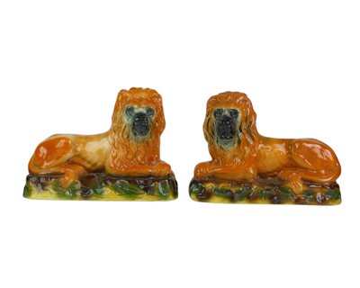 Lot 553 - A pair of pottery recumbent lion figures.