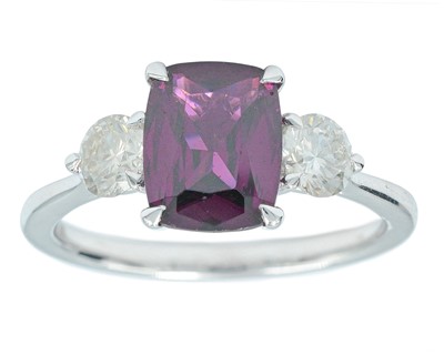 Lot 139 - A platinum three-stone ring, set with a cushion step cut almandine garnet and diamonds.