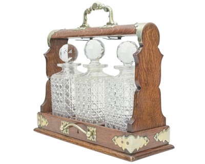 Lot 76 - An Edwardian oak three bottle tantalus.