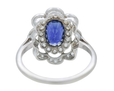 Lot An Art Deco oval blue sapphire and millgrain diamond set white metal ring.