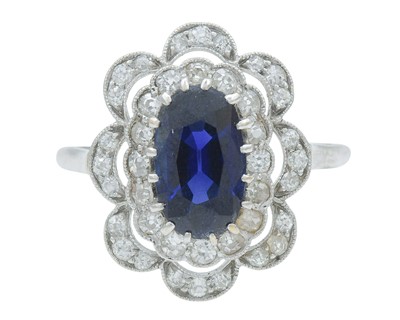 Lot An Art Deco oval blue sapphire and millgrain diamond set white metal ring.