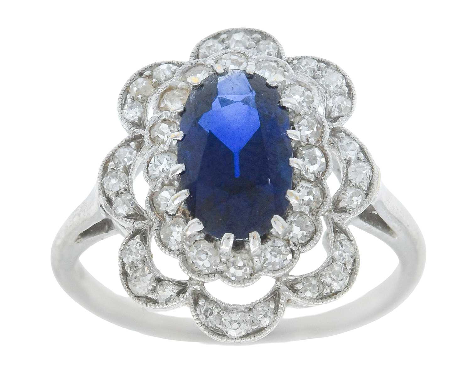Lot An Art Deco oval blue sapphire and millgrain diamond set white metal ring.