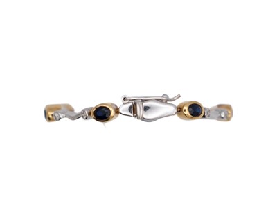 Lot 45 - A modern 18k yellow and white gold oval blue sapphire and diamond set bracelet.