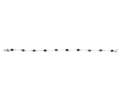 Lot 45 - A modern 18k yellow and white gold oval blue sapphire and diamond set bracelet.