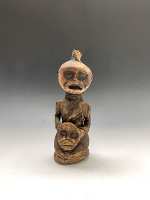 Lot 184 - An African carved wood figure holding a mask,...