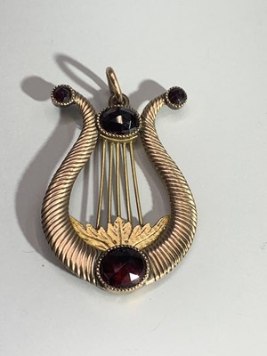 Lot 2470 - A Grand Tour lyre pendant set with garnets in...