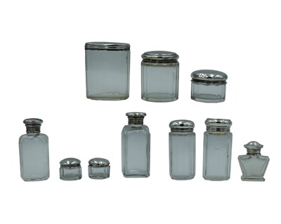 Lot 248 - An assortment of Victorian and later silver-lidded cosmetic jars and pots.