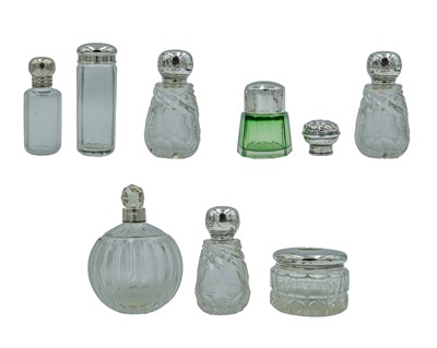 Lot 146 - A selection of silver-lidded cosmetic jars and scent bottles.