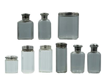 Lot 214 - A medley of Victorian and later silver lidded scent bottles and cosmetic jars.