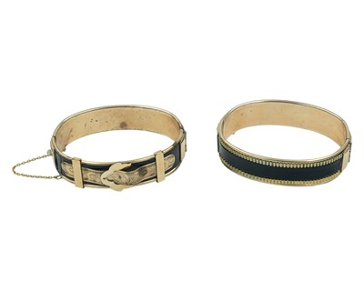 Lot 498 - Two Victorian rose gold-covered metal-core hinged mourning bangles with black enamel.