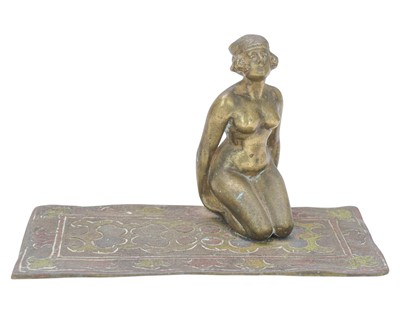 Lot 24 - A cold painted bronze figure of a female nude kneeling on a carpet.