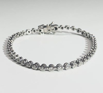 Lot 664 - An 18ct white gold tennis bracelet, set with a...