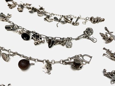 Lot 268 - A large collection of silver charms on three bracelets and loose.