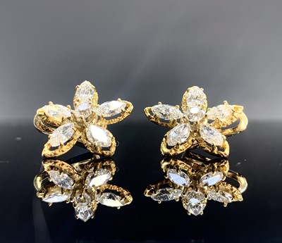 Lot 557 - A pair of diamond flowerhead earrings each has...