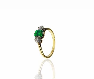 Lot 283 - An 18ct gold ring set an emerald and two...