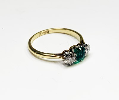 Lot 283 - An 18ct gold ring set an emerald and two...