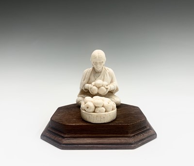 Lot 1068 - An Indian ivory model of a seated fruit vendor,...
