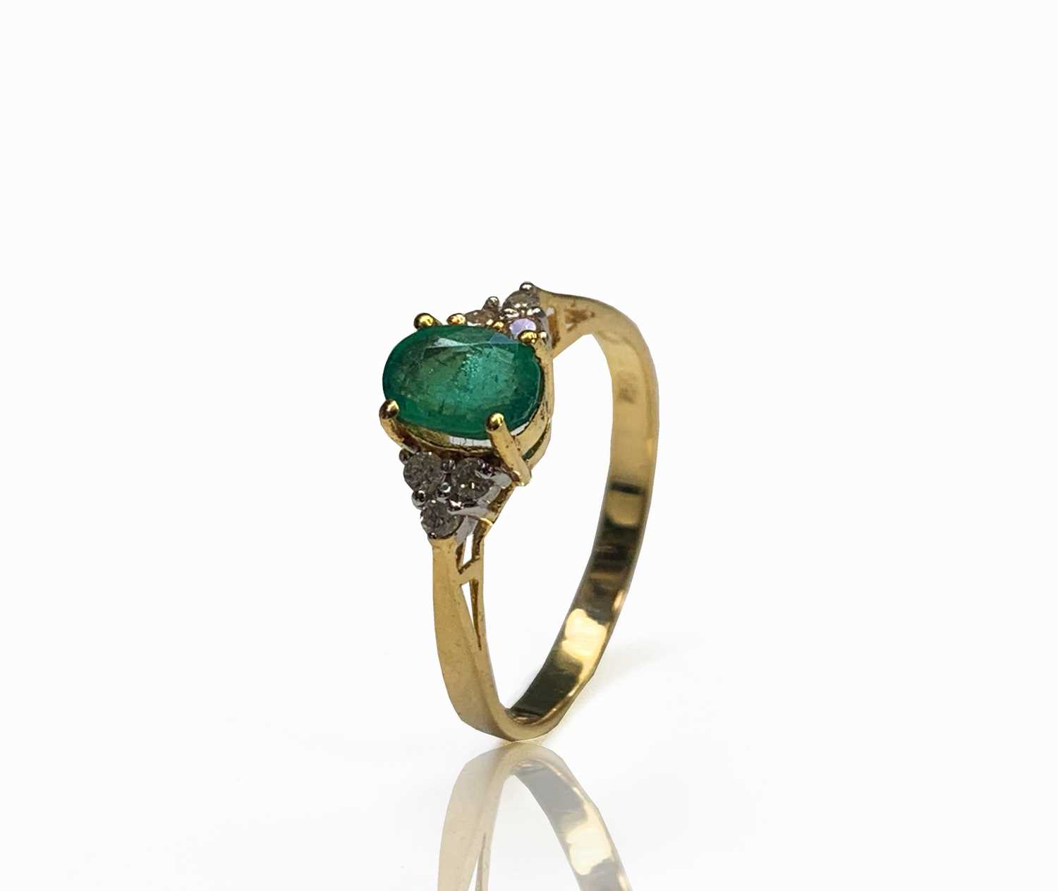 Lot 240 - An 18ct gold ring set with an emerald flanked...