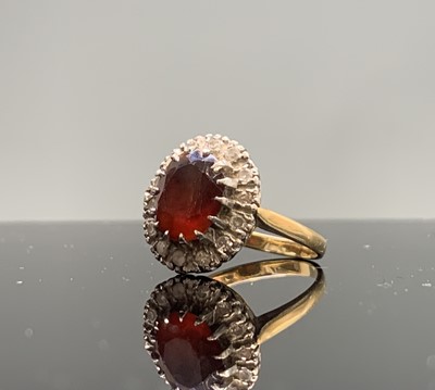 Lot 198 - A gold ring with an oval red stone and diamond...