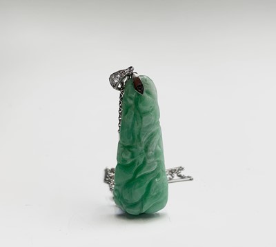 Lot 213 - A 1920s carved jade pebdant mounted in white...