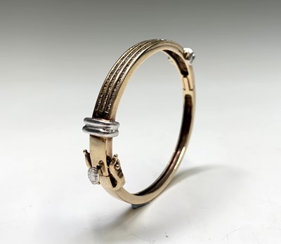 Lot 404 - A 9ct yellow and white gold hinged bangle with...
