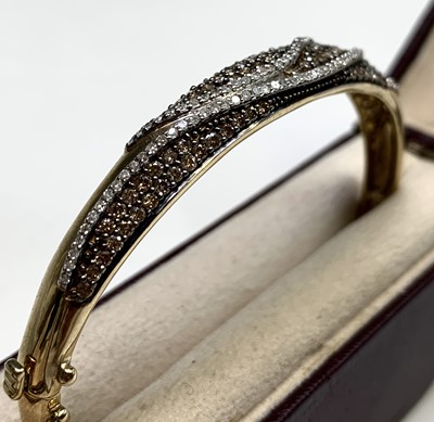 Lot 134 - A gold hinged bangle pave and line set with...