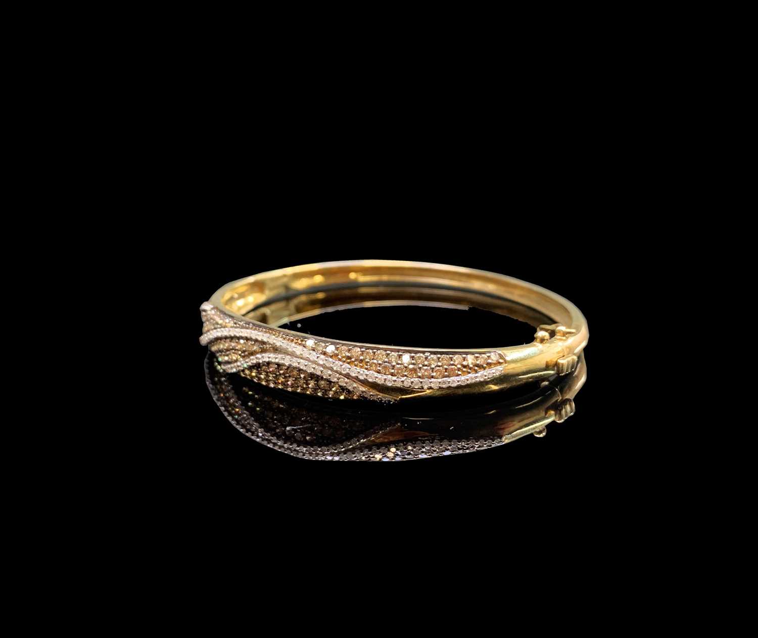Lot 134 - A gold hinged bangle pave and line set with...