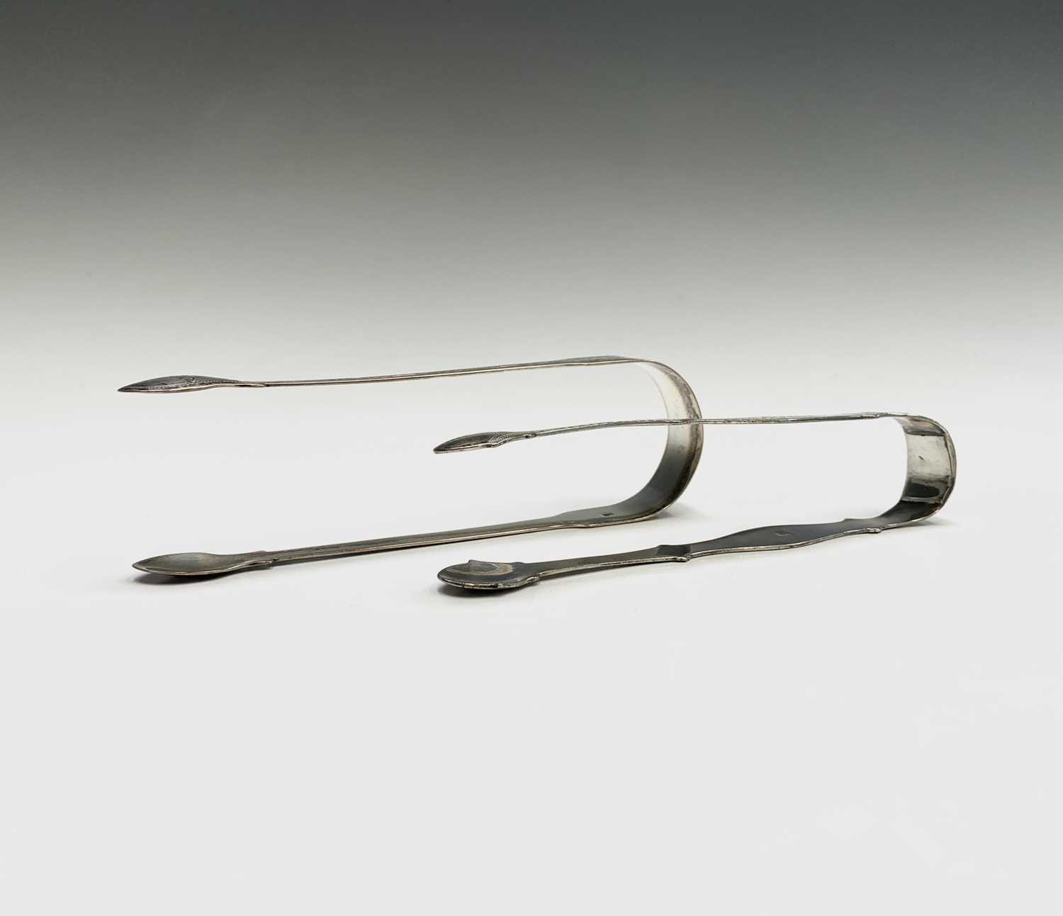 Lot 1028 - Two pairs of silver sugar tongs each by Peter...