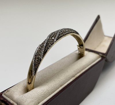 Lot 135 - A contemporary 9ct gold hinged bangle wreathed...