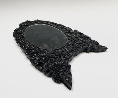 Lot 1066 - An Indian carved ebonised oval mirror, circa...