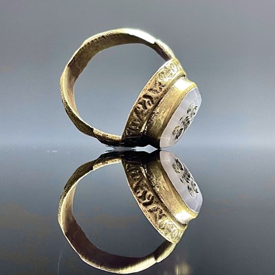 Lot 688 - A cast bronze ring set with an oval white...