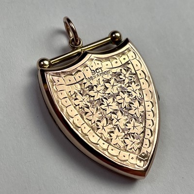 Lot 613 - A 9ct gold shield shaped foliate engraved...