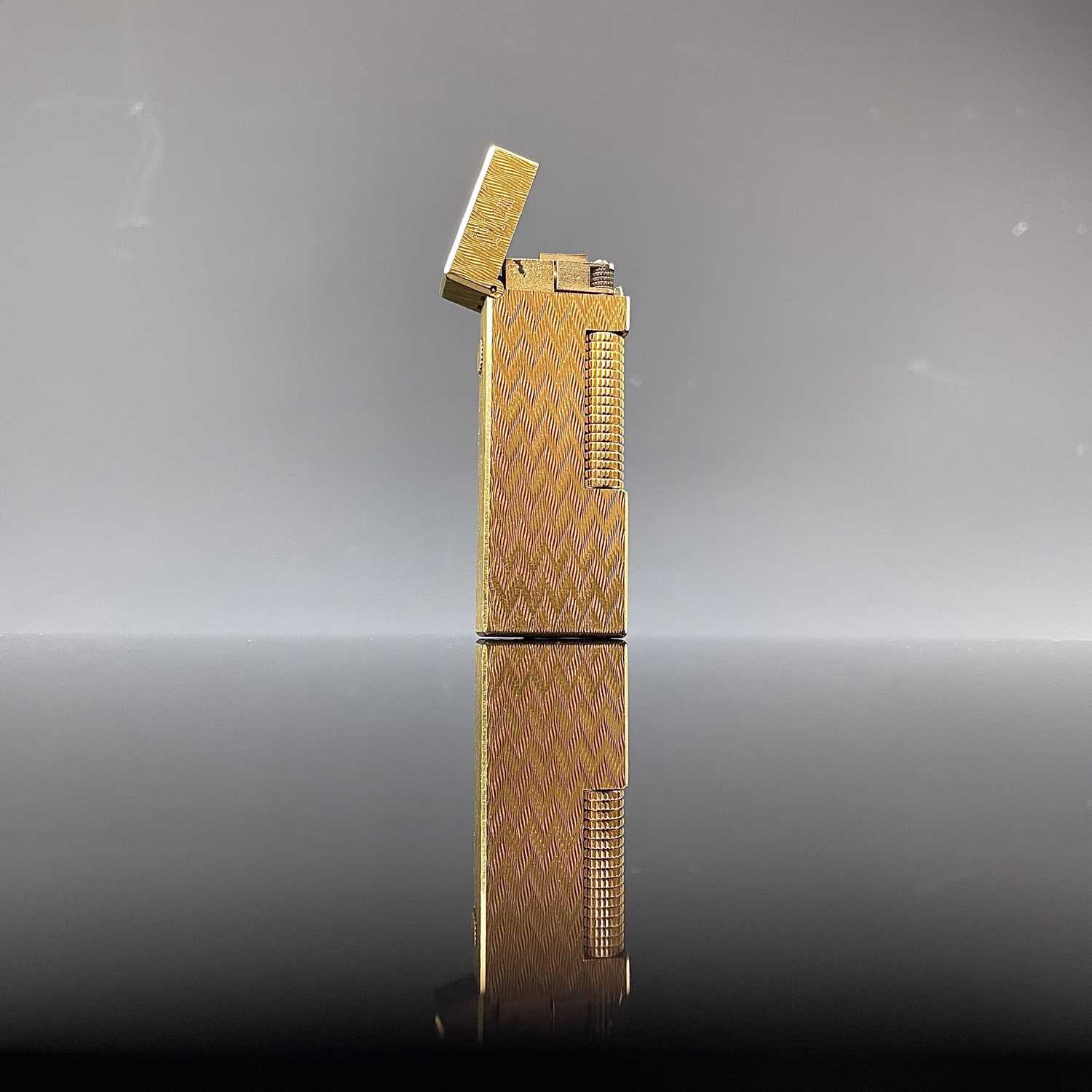 Lot 214 - A Dunhill gold plated engine turned lighter.