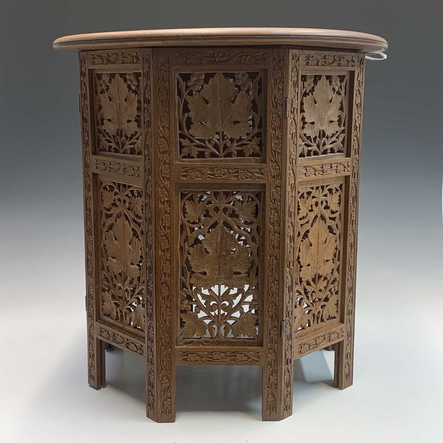 Lot 1054 - An Indian carved wood folding occasional table,...