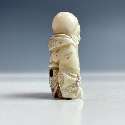 Lot 547 - A Japanese netsuke of a seated man holding a...